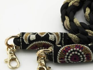 Gros plan sur les embouts brodés du cordon Baroque Bohème Ambrée noir et doré avec finitions rouges et mousquetons dorés