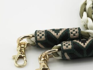 Gros plan sur les embouts brodés du cordon Ambrée kaki et écru avec motifs géométriques et mousquetons dorés