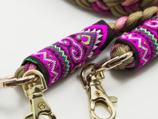 Gros plan sur les embouts brodés du cordon Ambrée rose et beige avec motifs fuchsia, violets et mousquetons dorés