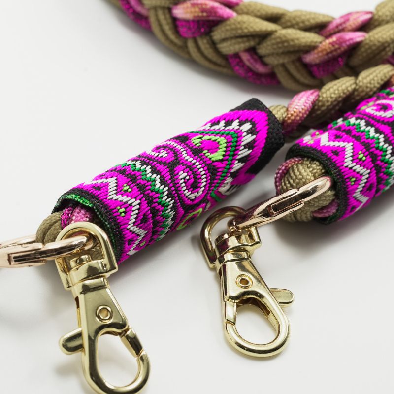 Gros plan sur les embouts brodés du cordon Ambrée rose et beige avec motifs fuchsia, violets et mousquetons dorés