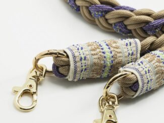 Gros plan sur les embouts brodés du cordon Ambrée lavande et beige avec mousquetons dorés