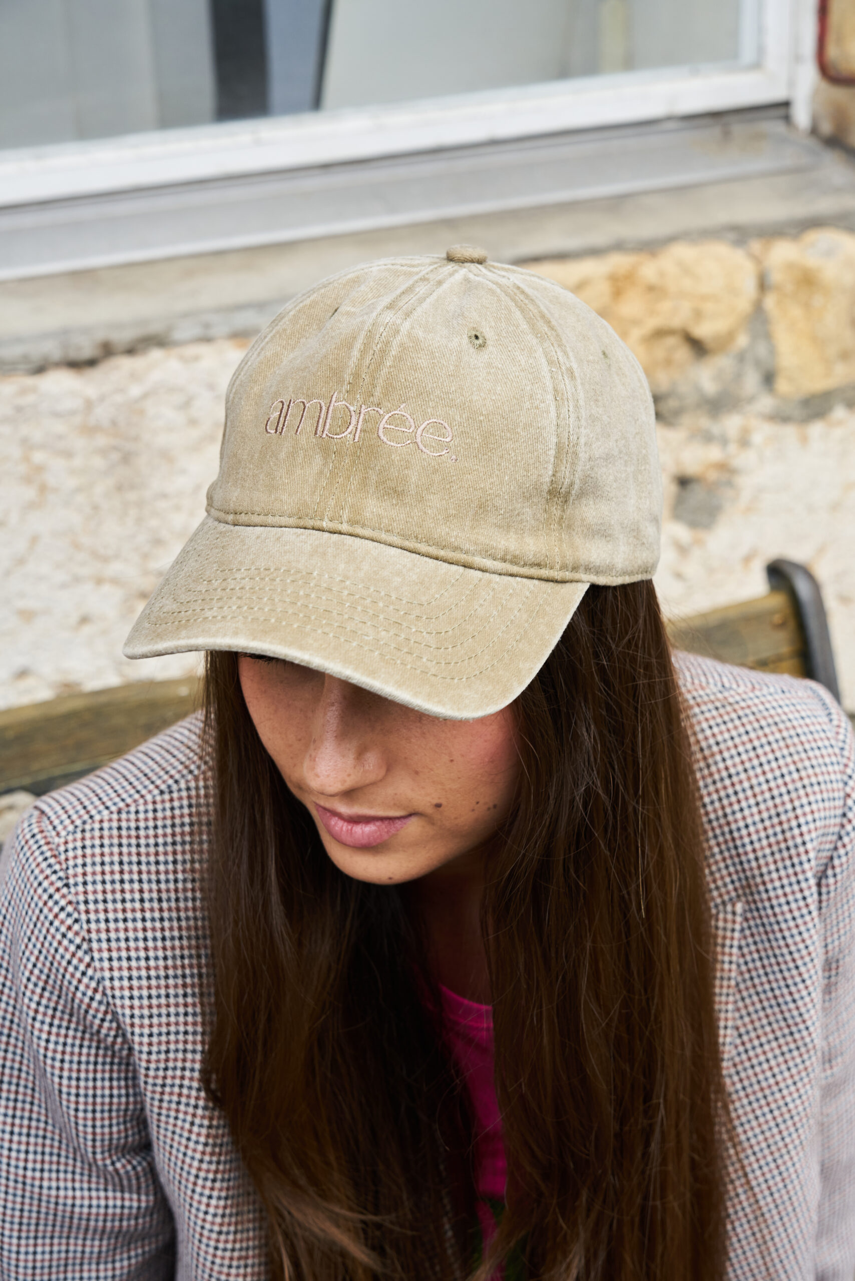 Femme de dos portant une casquette noire Ambrée Suisse dans un décor urbain, style sobre et contemporain